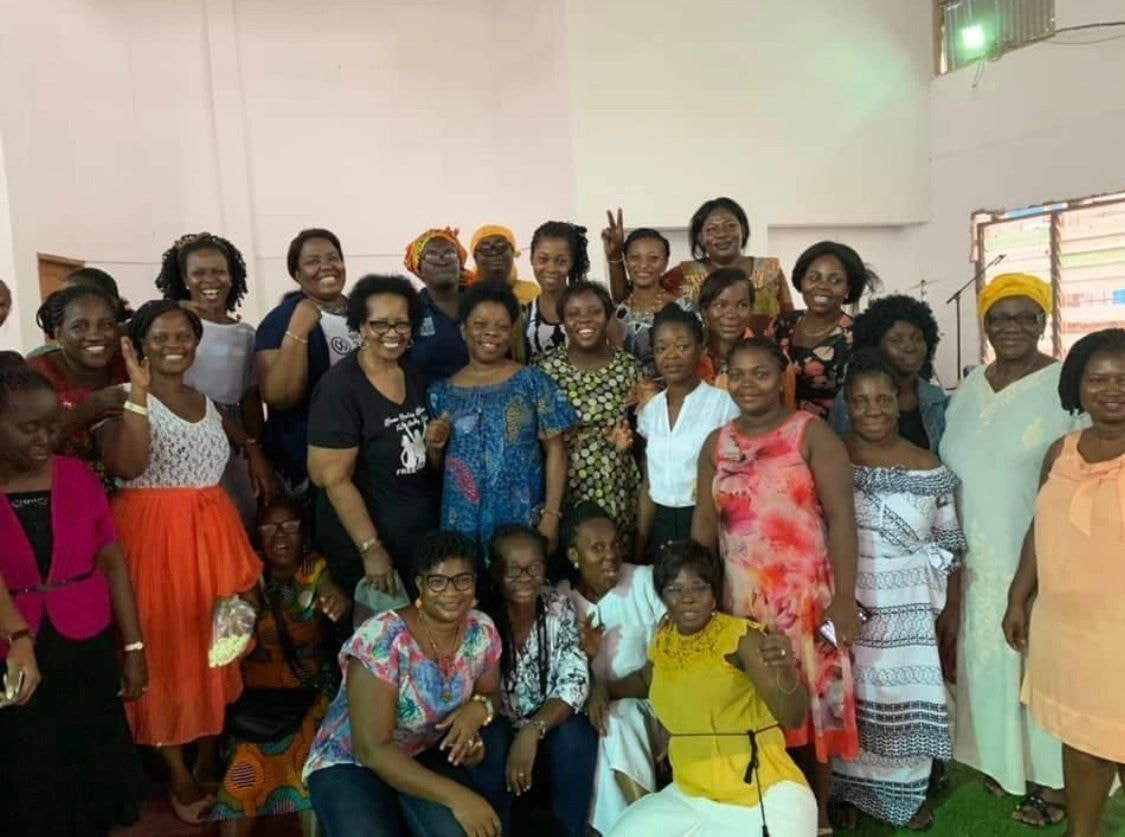 A large group of women in colorful dresses and head wraps gathered for a celebration