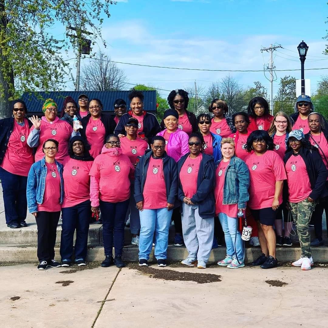 A large group of women in matching shirts gathered together on sunny outdoor steps